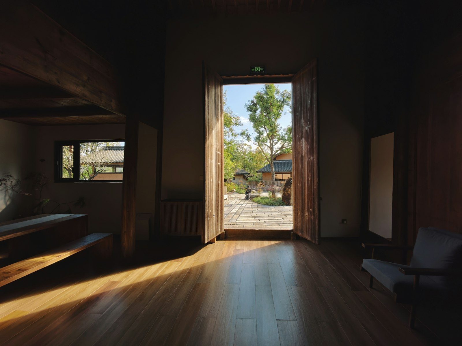 An open doorway leading from a dark room into a sunlit courtyard